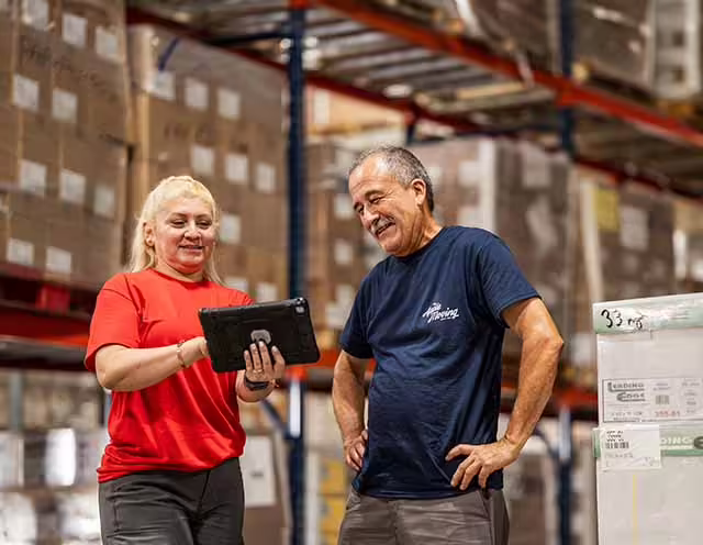 Moving professionals handling wrapped items in a commercial storage space